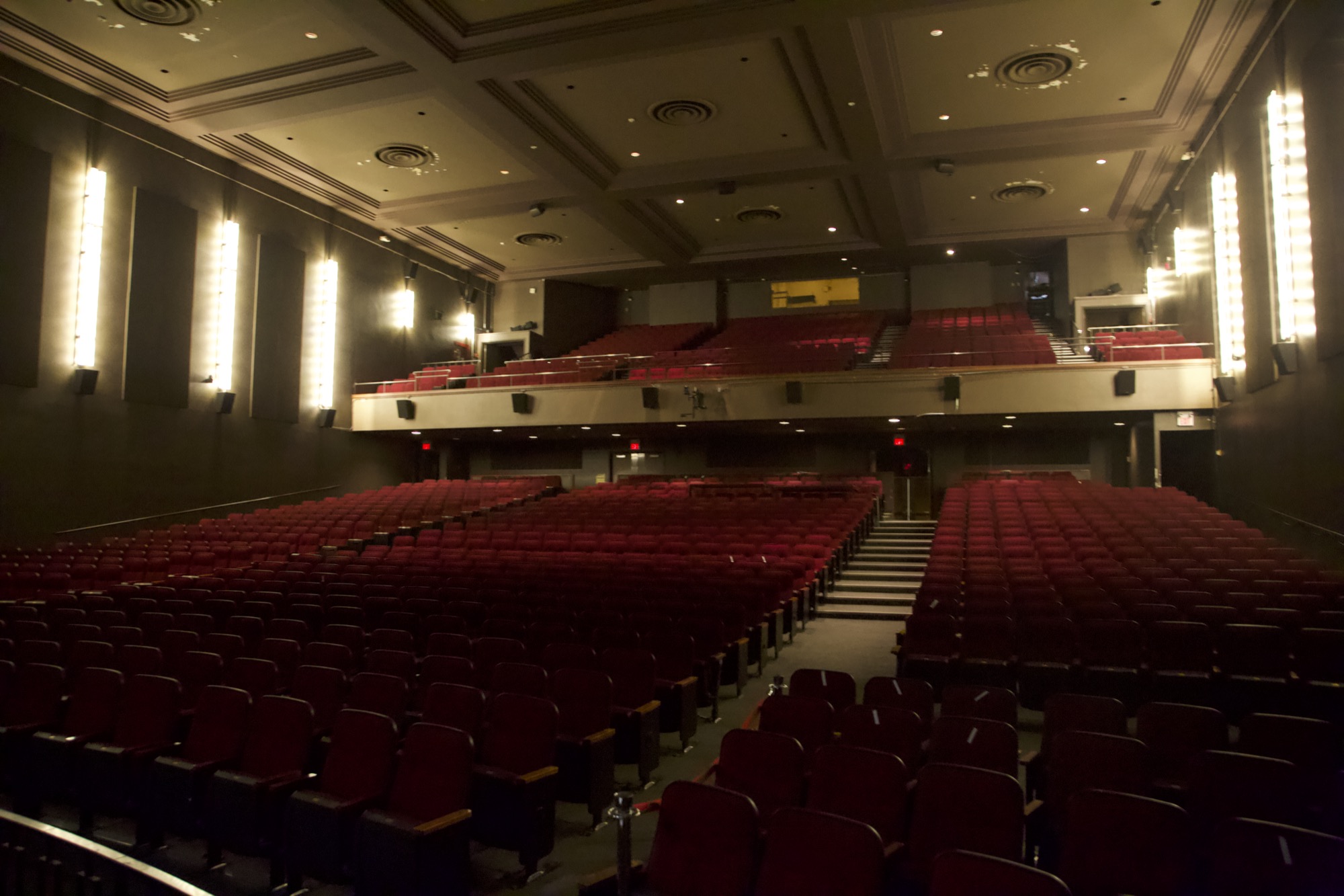 A wide symmetrical view of the auditorium and balcony filled with red seats
