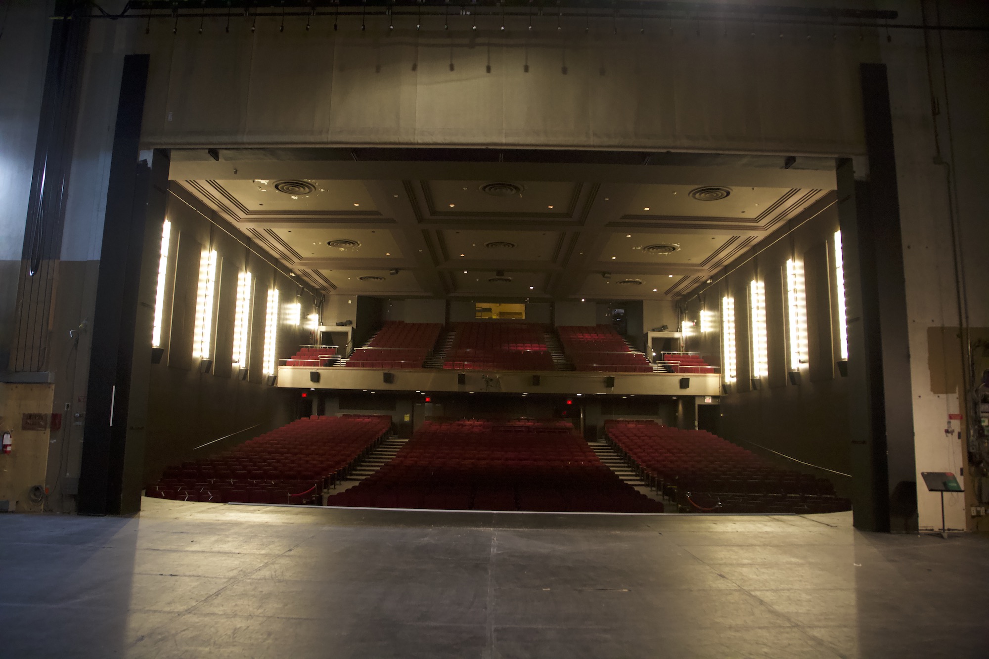 The stage floor looking out to the house, work lights burning at the sides.